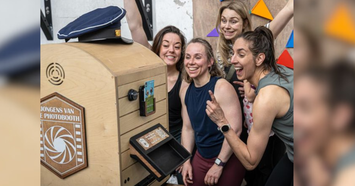 Een groep vrolijke vrienden maakt plezier met een mooie houten photobooth to go op een feest.